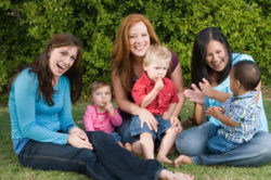 three moms laughing with children