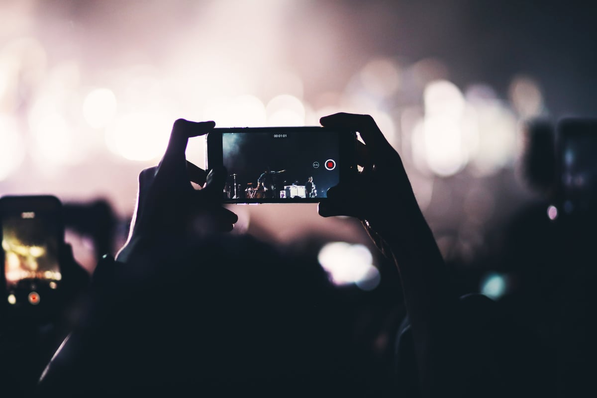 person filming concert on phone