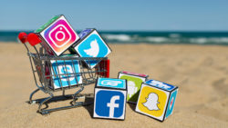 social media icons on blocks in shopping cart on beach