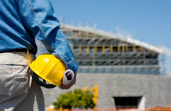 man with yellow hard hat standing in front of building