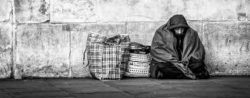 homeless person sitting against wall